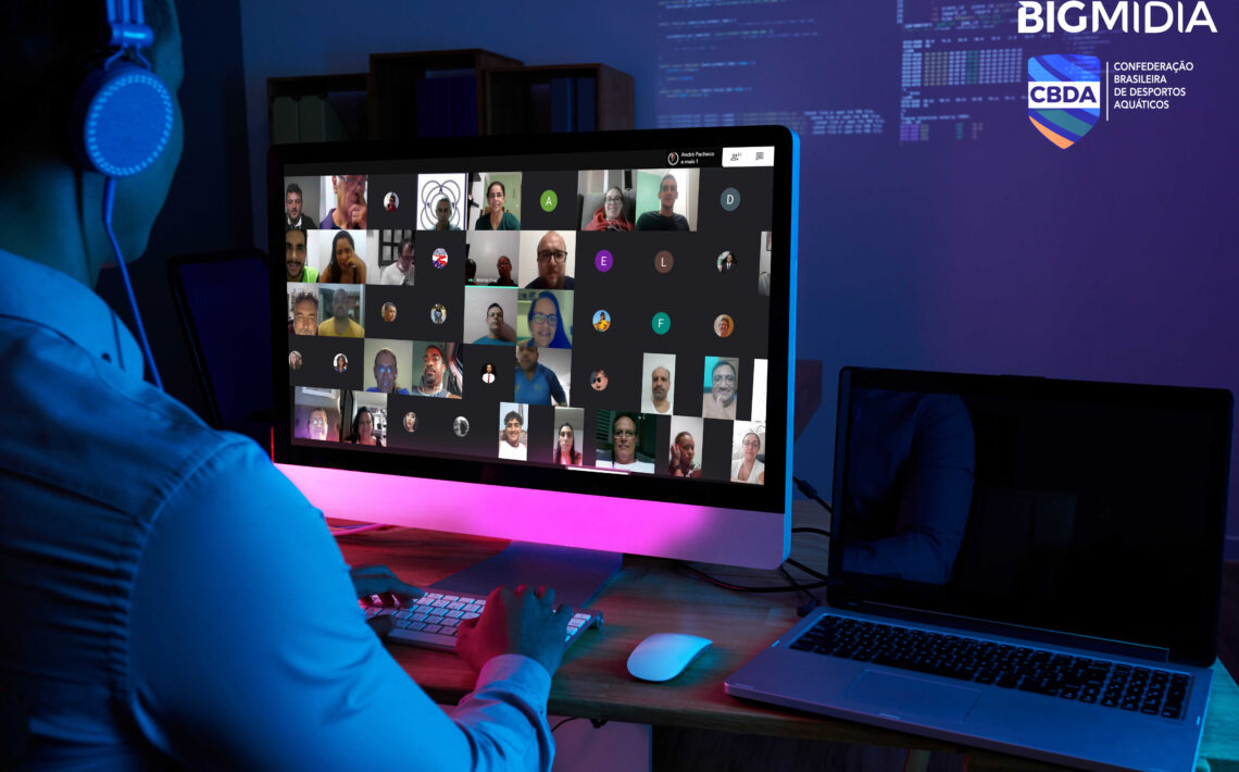 Imagem com uma pessoa de frente para um computador. Na tela do computador estão os participantes do curso online da Bigmidia.